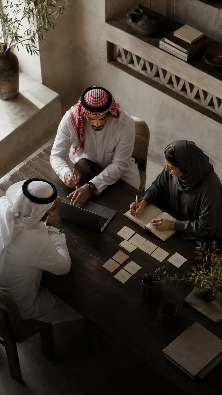 مشهد توضيحي لفريق سعودي يعمل حول طاولة داخل استديو للذكاء الاصطناعي التطبيقي